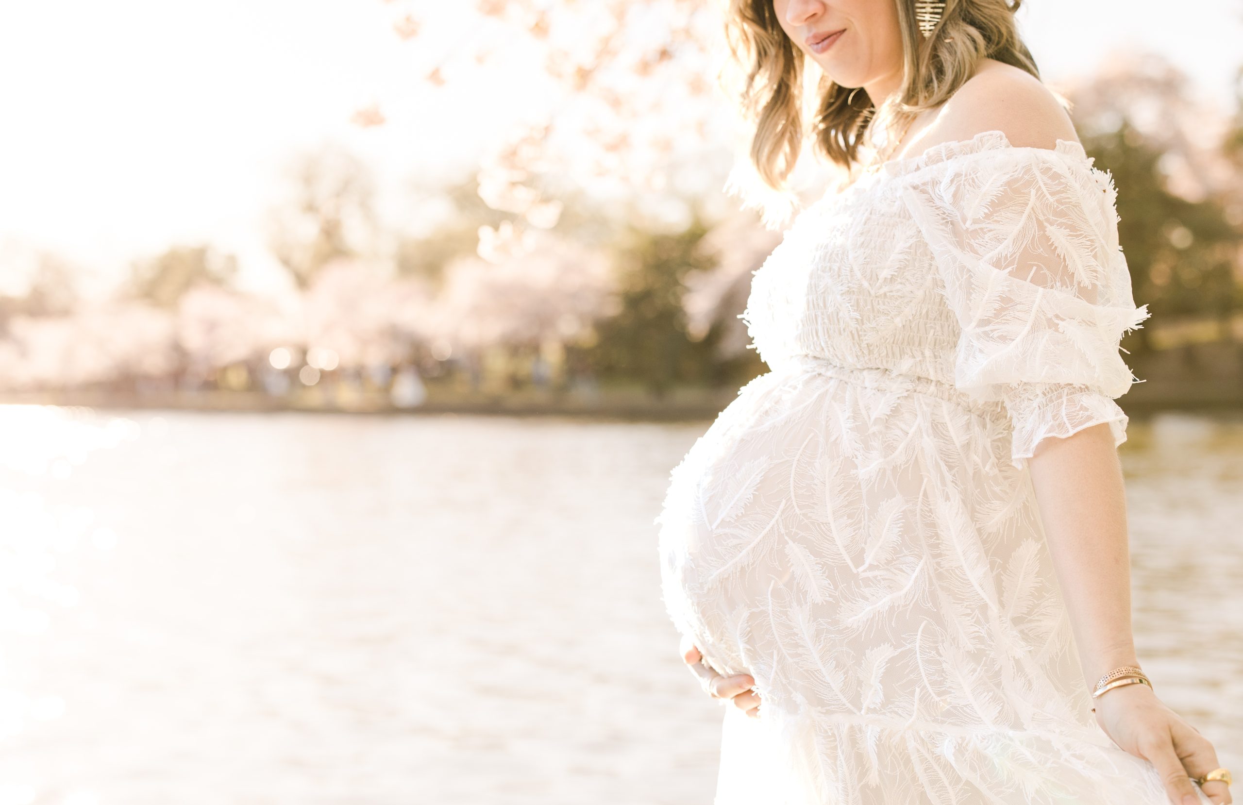 mom-to-be in a white feathered dress at the Tidal Basin during peak Cherry Blossom Bloom