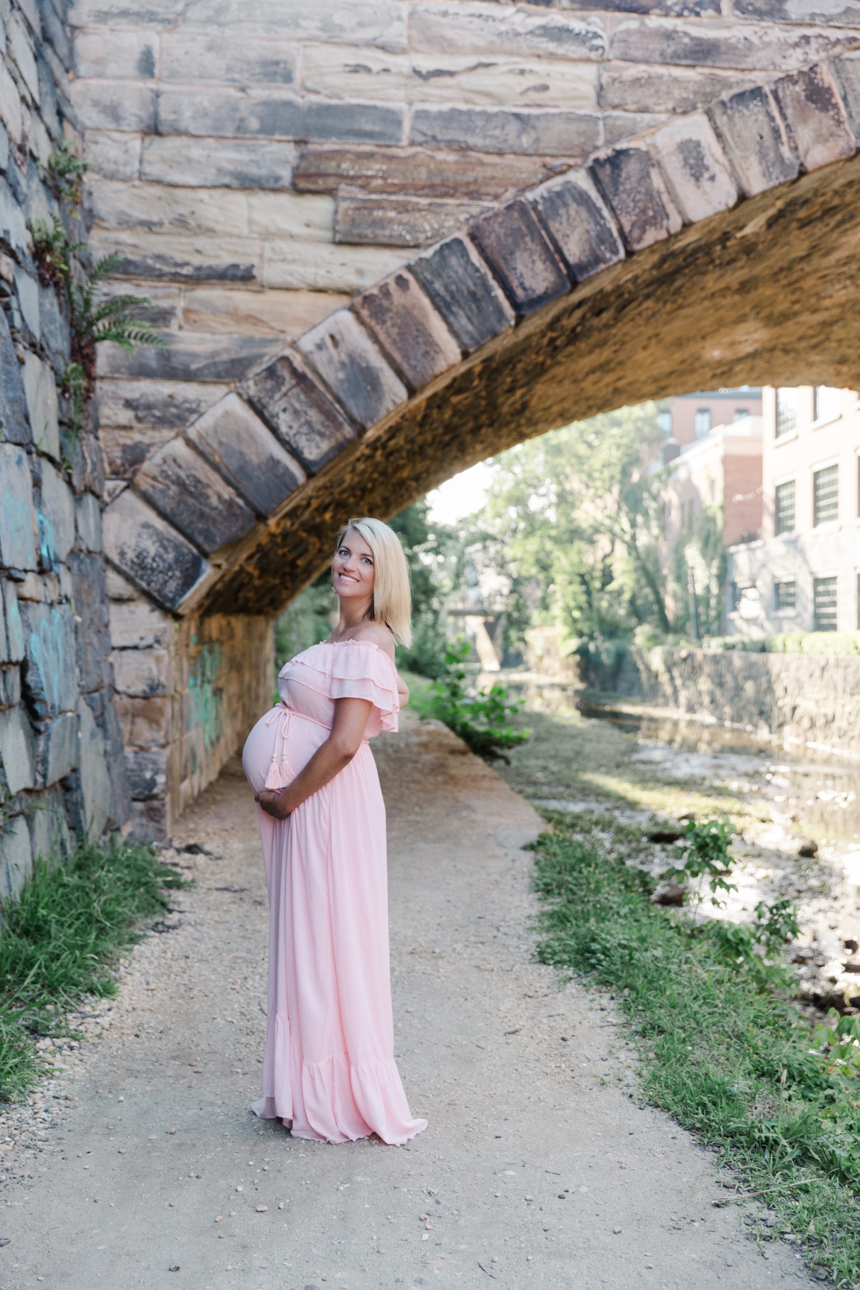 mom-to-be wearing a pink dress posed by the canal in Georgetown by Northern Virginia Maternity Photographer