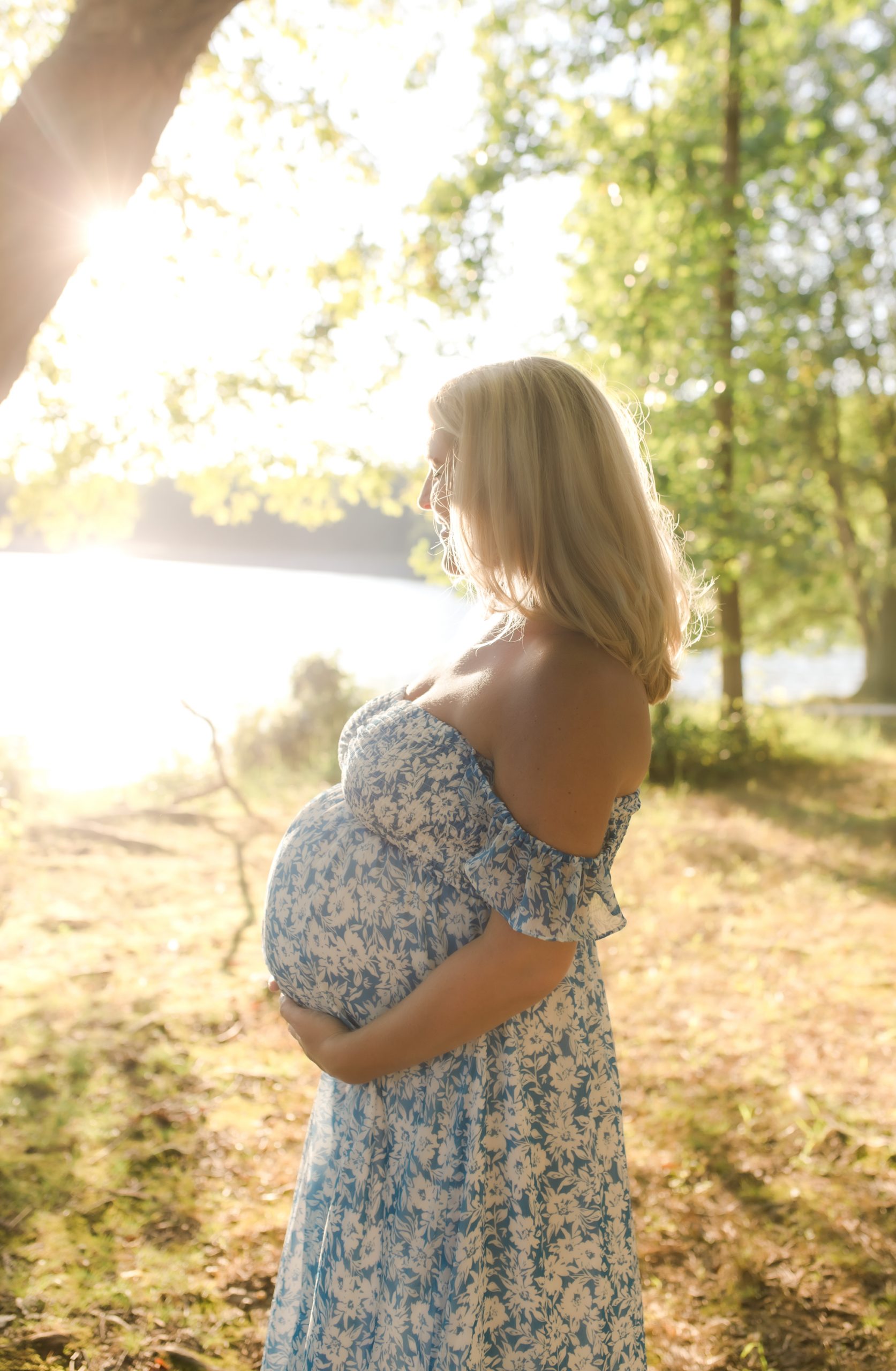twin mom-to-be posing in back-lit image by a lake by northern virginia maternity photographer
