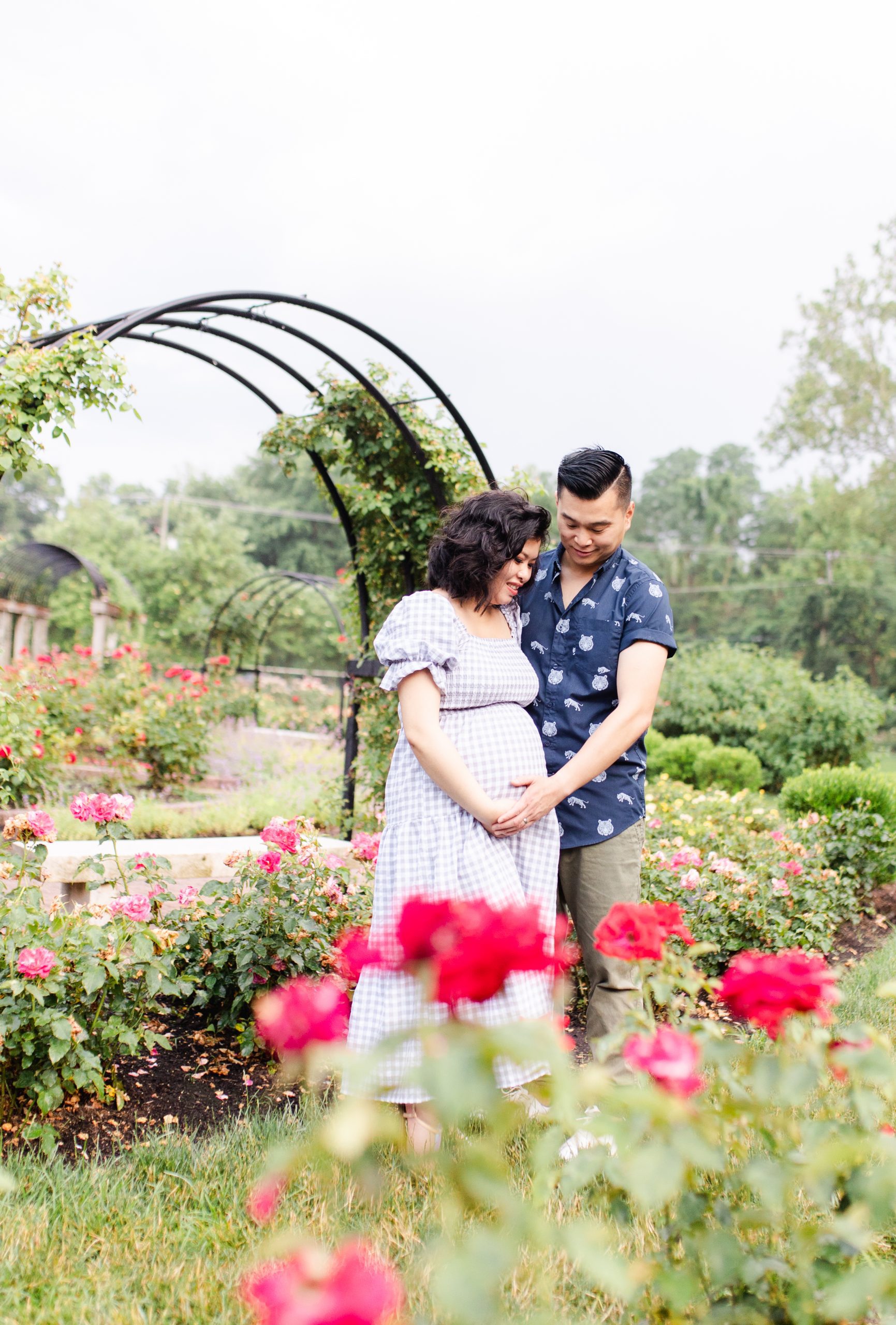 dad and mom-to-be posing amongst the roses at bon air park by northern virginia maternity photographer