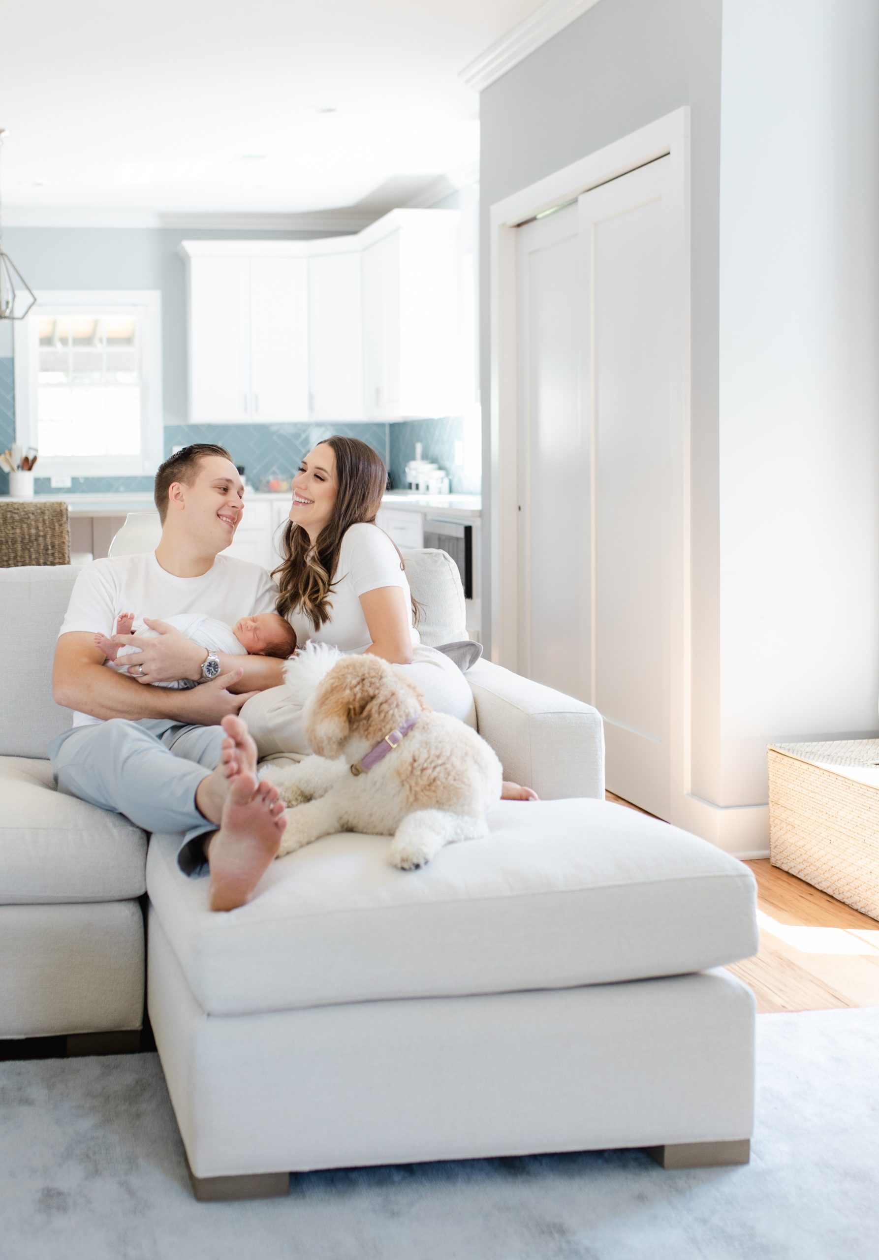 Parents snuggled on couch with newborn baby and dog by Northern Virginia Newborn Photographer