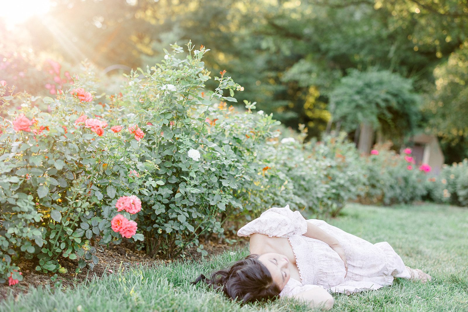 expecting mom laying down during maternity session amongst the roses