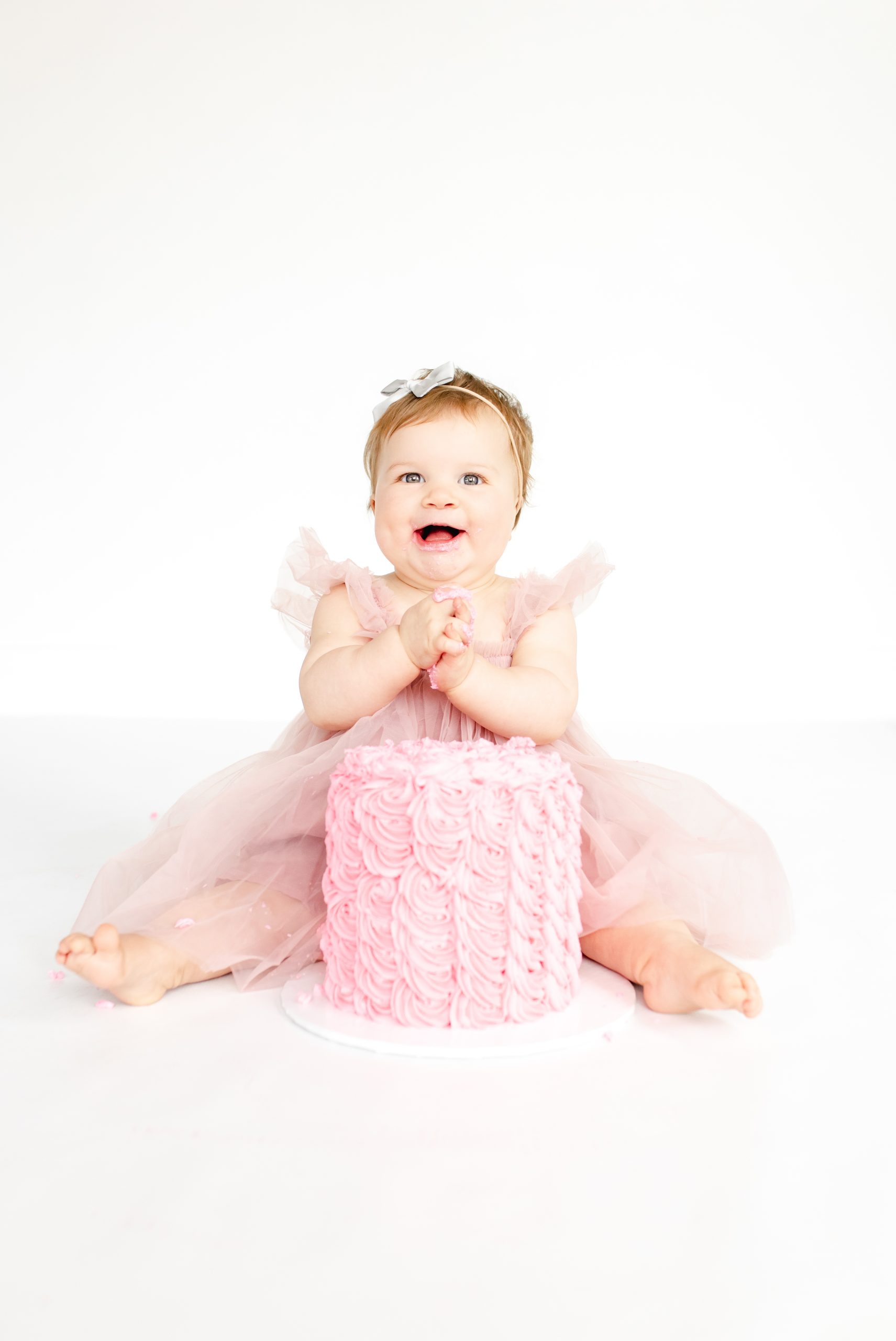 happy one year old baby girl with a pink cake for a cake smash with Northern Virginia Baby Photographer