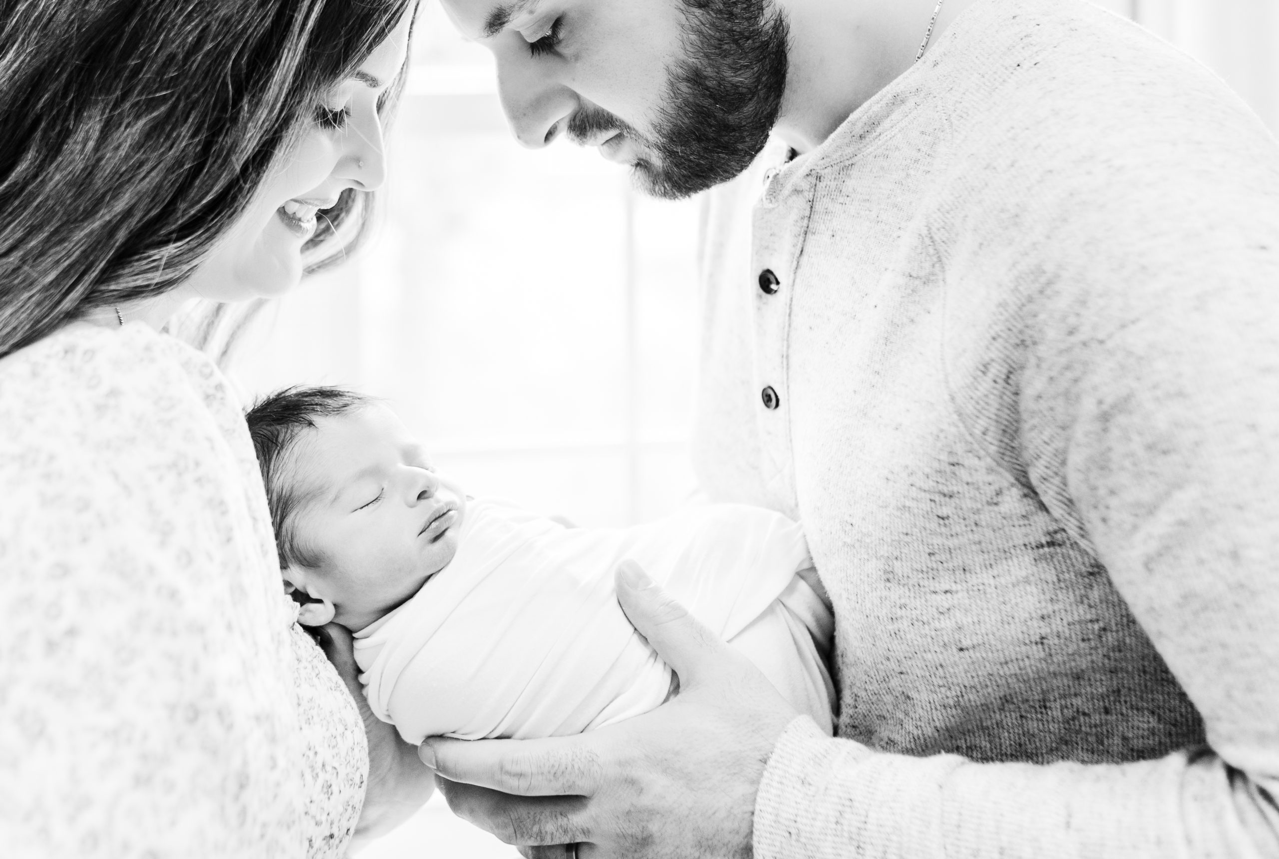 backlit black and white close up of mom and dad admiring newborn baby by DC Newborn Photographer