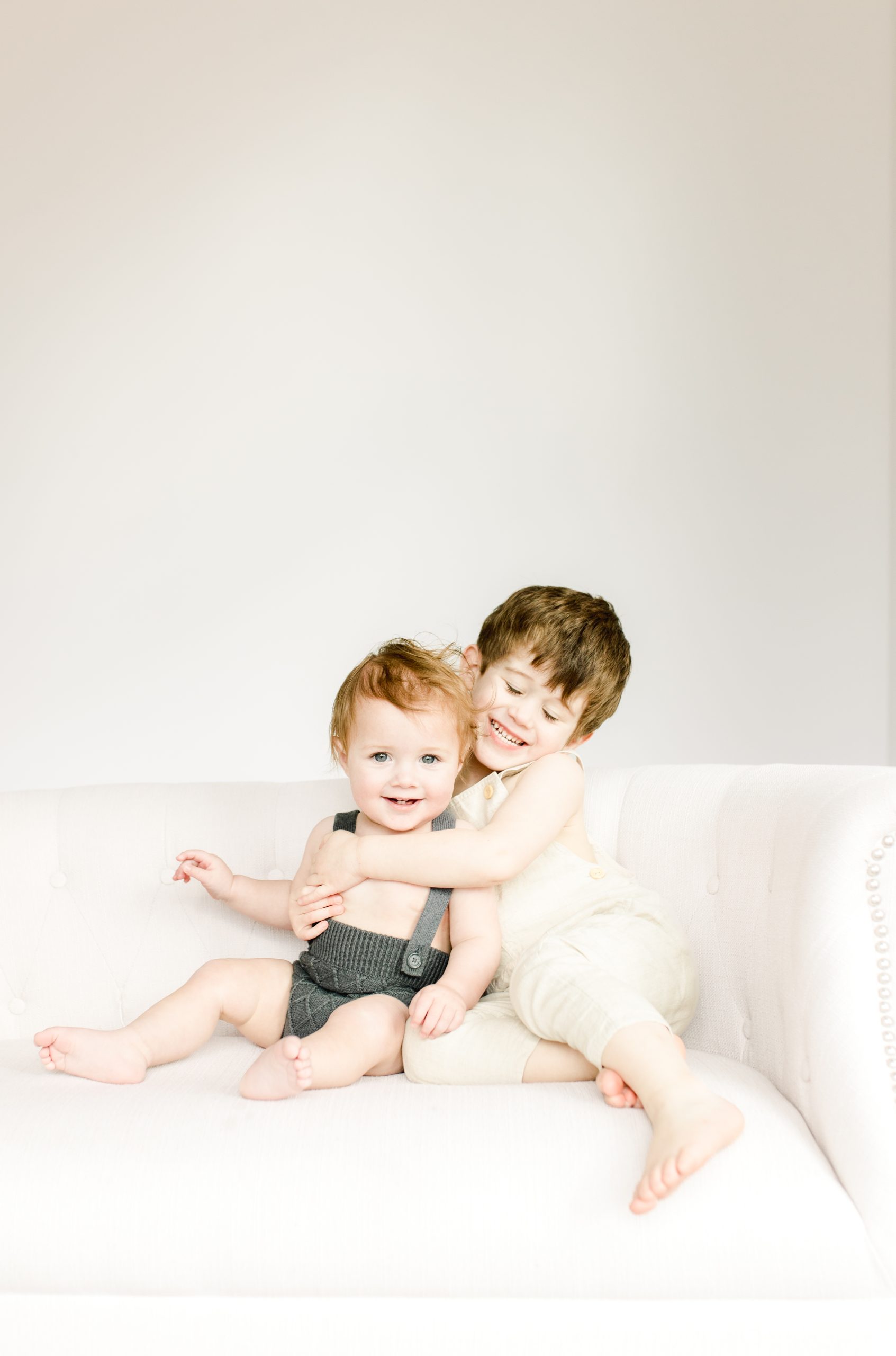 big brother hugging little brother on couch by Northern Virginia Baby Photographer