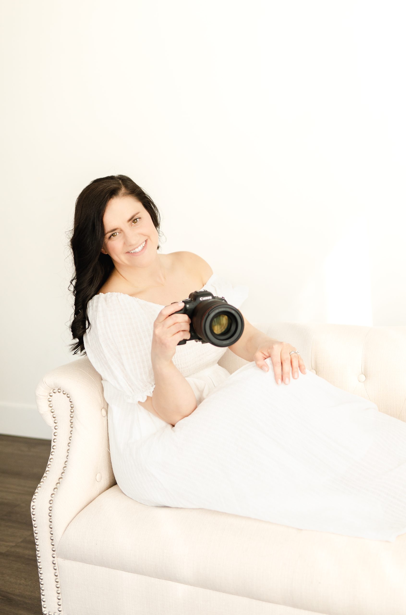 Northern Virginia Newborn Photographer sitting on couch with her camera