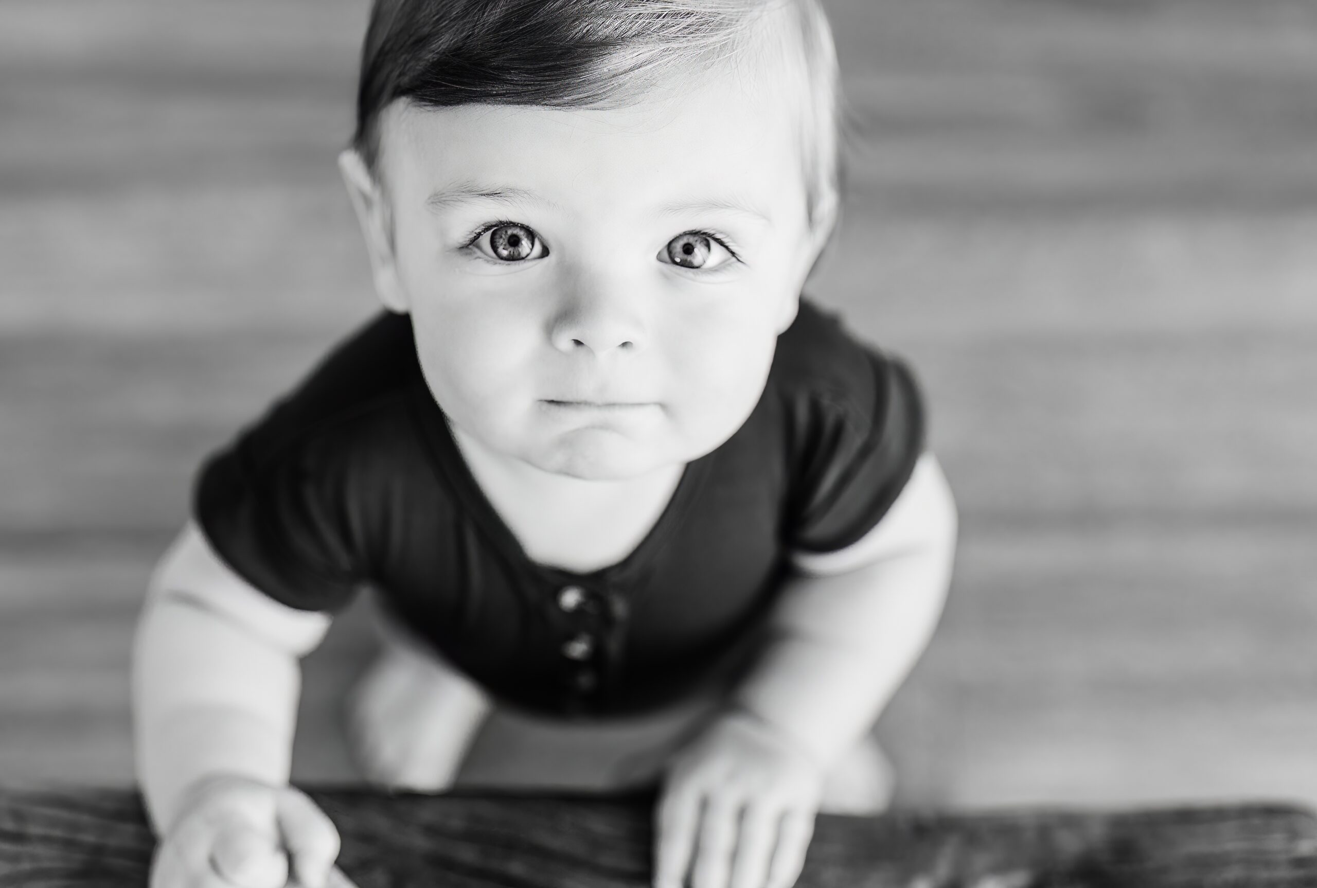 Black and white portrait of a one year old boy looking up at the camera.
