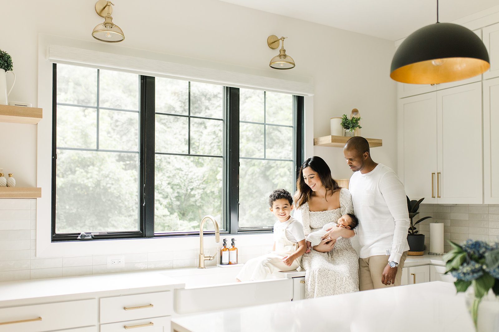 family together in the kitchen with toddler playing in the sink