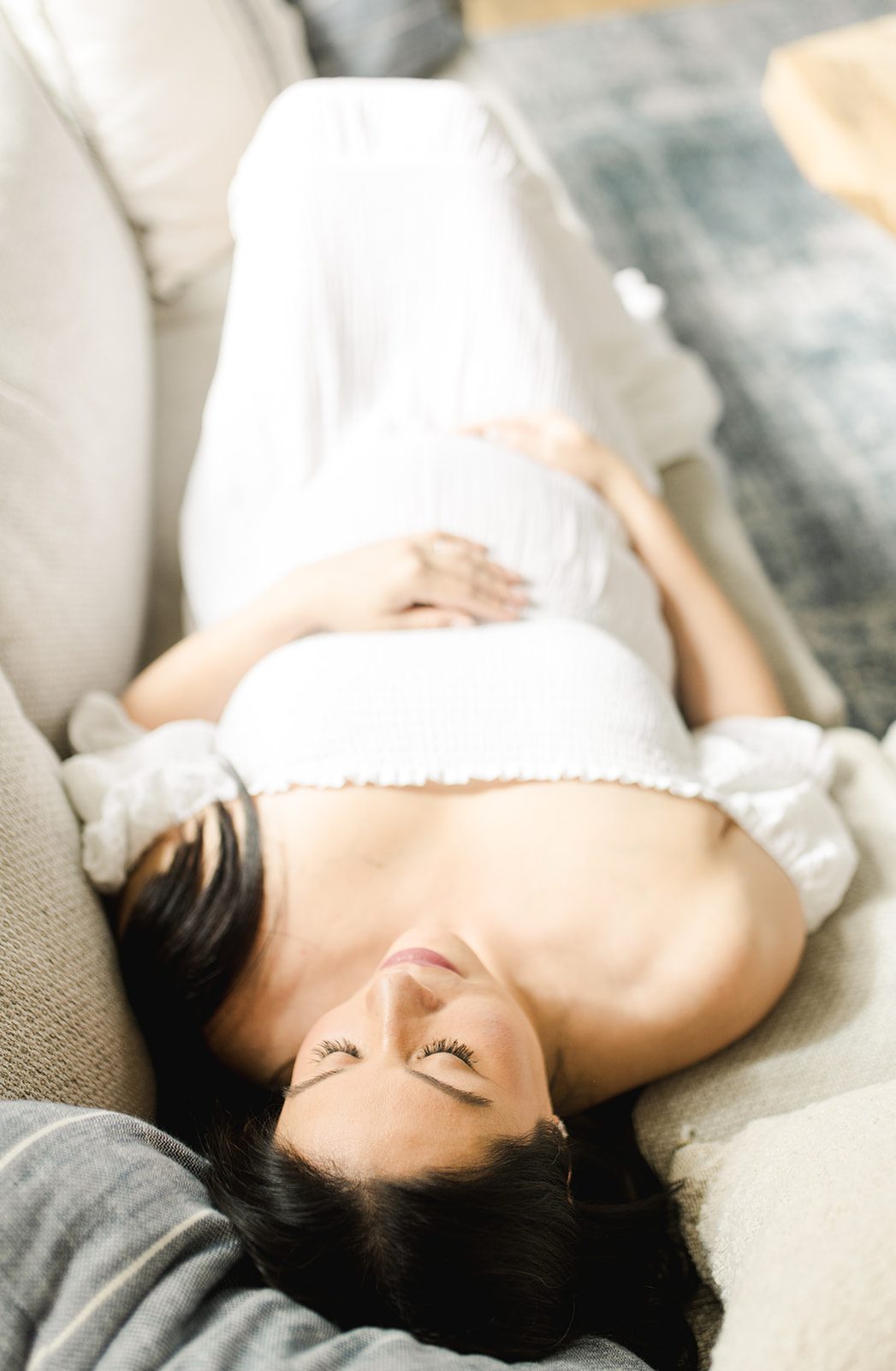 expecting mom laying on the couch during her in-home maternity session