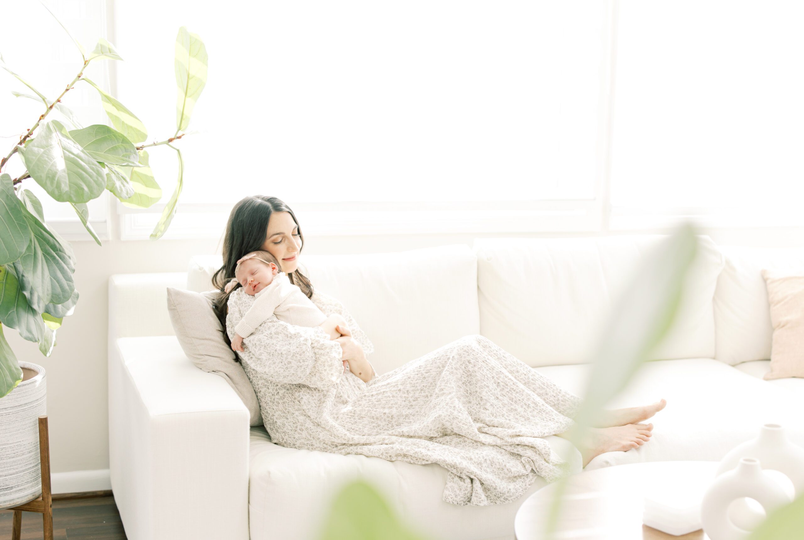 Mom relaxing on couch snuggling her newborn baby