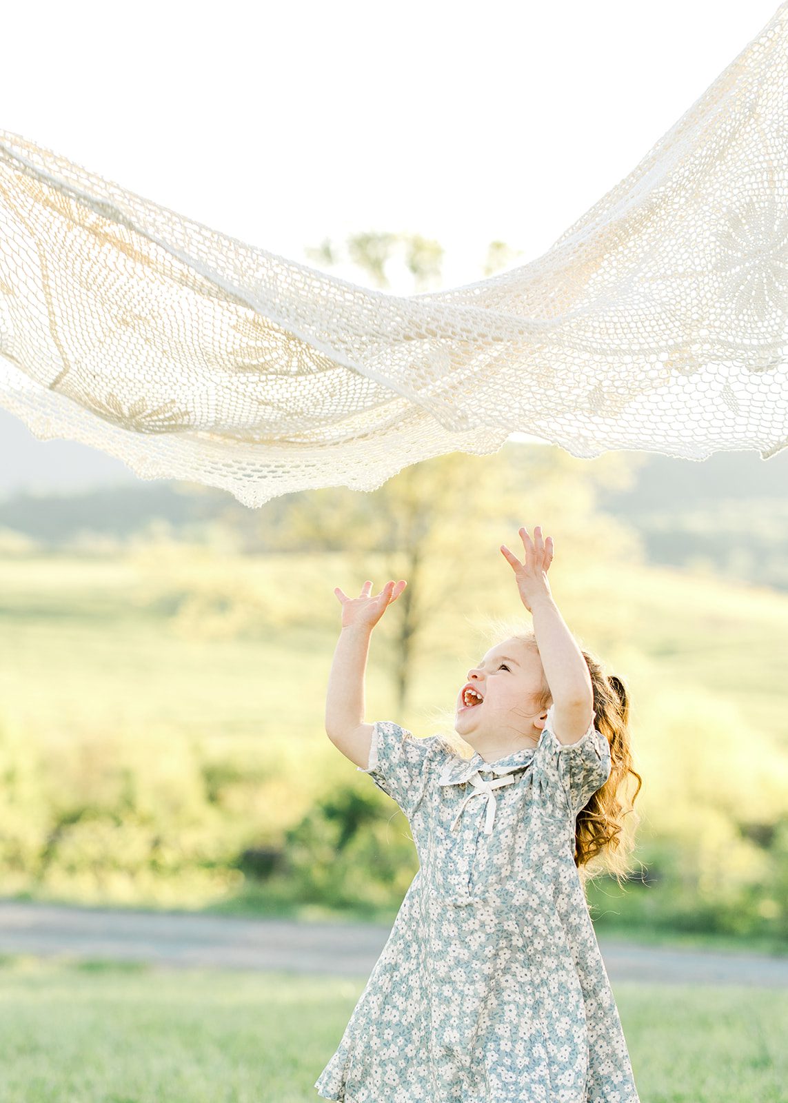 toddler girl playing under a blanket happily